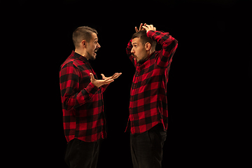 Image showing Young handsome man arguing with himself on black studio background.