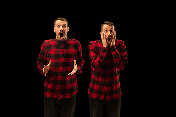 Image showing Young handsome man arguing with himself on black studio background.