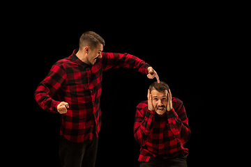 Image showing Young handsome man arguing with himself on black studio background.