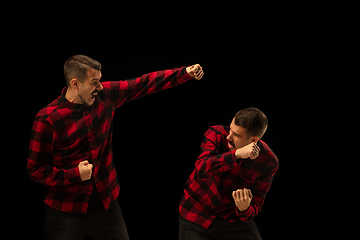 Image showing Young handsome man arguing with himself on black studio background.