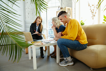 Image showing Interior designer working with young couple. Lovely family and professional designer or architector.