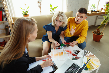 Image showing Interior designer working with young couple. Lovely family and professional designer or architector.