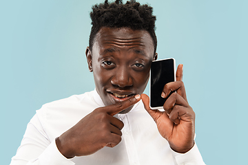 Image showing Young african-american man isolated on blue studio background, human emotions concept.