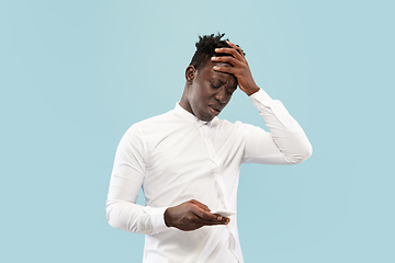 Image showing Young african-american man isolated on blue studio background, human emotions concept.