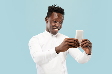 Image showing Young african-american man isolated on blue studio background, human emotions concept.