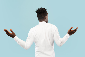 Image showing Young african-american man isolated on blue studio background, human emotions concept.