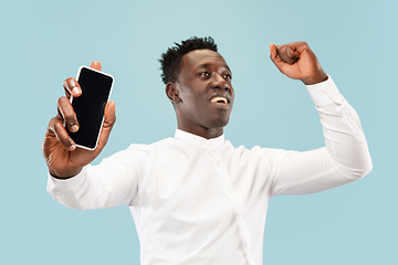 Image showing Young african-american man isolated on blue studio background, human emotions concept.