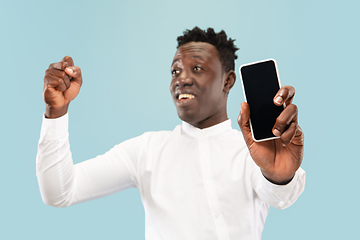 Image showing Young african-american man isolated on blue studio background, human emotions concept.