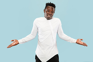 Image showing Young african-american man isolated on blue studio background, human emotions concept.