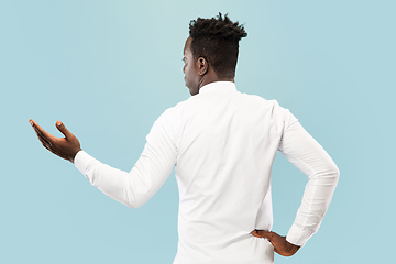 Image showing Young african-american man isolated on blue studio background, human emotions concept.