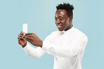 Image showing Young african-american man isolated on blue studio background, human emotions concept.