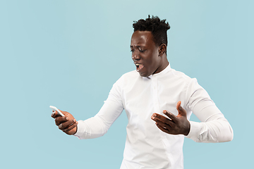 Image showing Young african-american man isolated on blue studio background, human emotions concept.