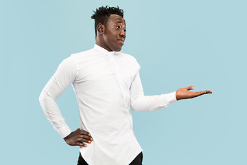 Image showing Young african-american man isolated on blue studio background, human emotions concept.