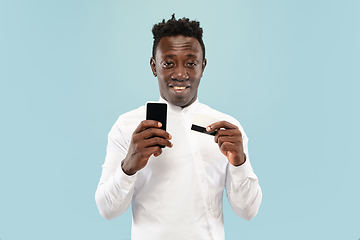 Image showing Young african-american man isolated on blue studio background, human emotions concept.