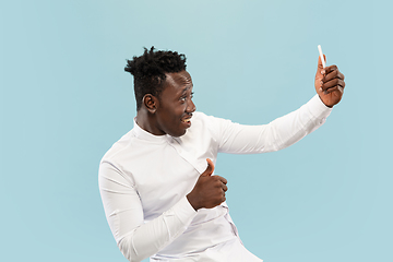 Image showing Young african-american man isolated on blue studio background, human emotions concept.