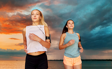 Image showing young women with earphones and smartphones running