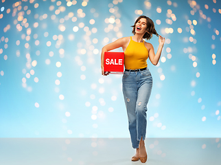 Image showing happy smiling young woman posing with sale sign