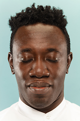 Image showing African-american young man\'s close up portrait on blue background