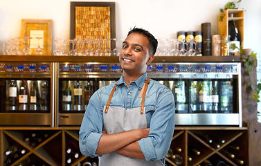 Image showing smiling indian barman or waiter in apron at bar