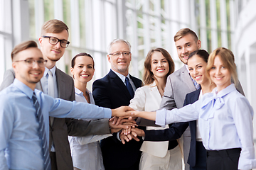 Image showing happy business people stacking hands at office