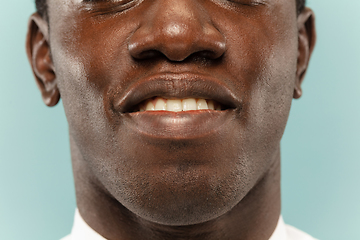 Image showing African-american young man\'s close up portrait on blue background