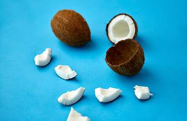 Image showing whole and cracked coconut on blue background