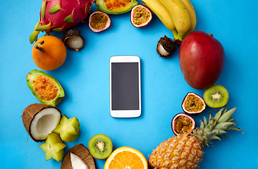 Image showing exotic fruits around smartphone on blue background
