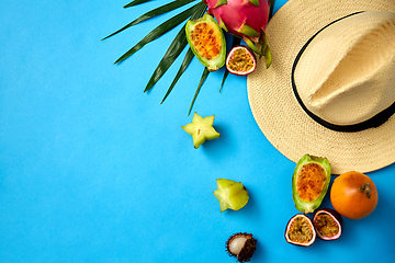 Image showing straw hat and exotic fruits on blue background