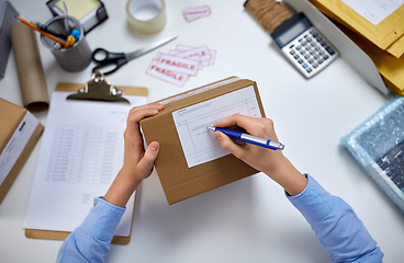 Image showing close up of hands filling form on parcel at office