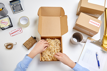 Image showing hands with straw filler in parcel at post office