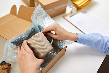 Image showing hands packing mug to parcel box at post office