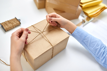 Image showing hands packing parcel and tying rope at post office