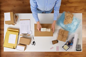 Image showing woman packing parcel box with adhesive tape