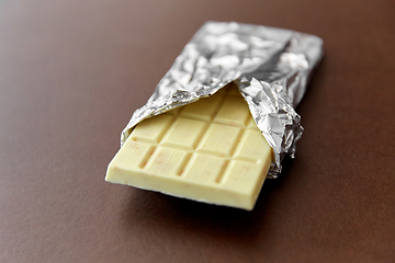 Image showing white chocolate bar in foil wrapper on brown