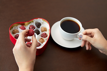 Image showing hands, candies in heart shaped box and coffee cup