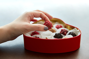 Image showing hand with candies in heart shaped chocolate box