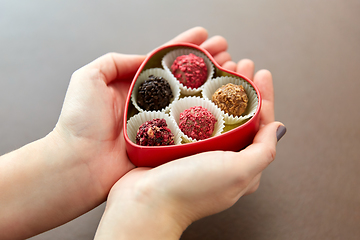 Image showing hands with candies in heart shaped chocolate box