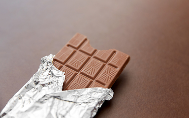 Image showing chocolate bar in foil wrapper on brown background