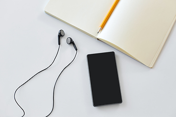 Image showing earphones, smartphone and notebook with pencil