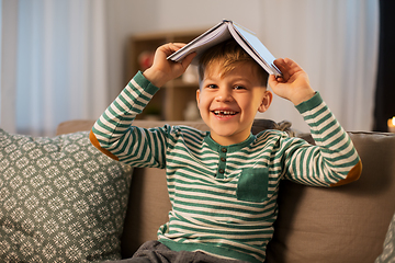 Image showing happy little boy with book having fun at home