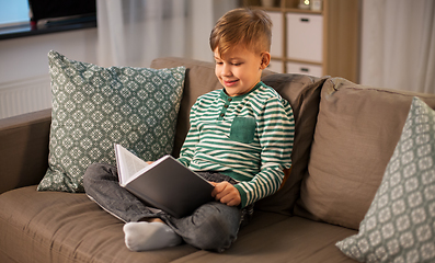 Image showing happy smiling little boy reading book at home