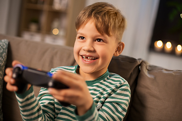 Image showing little boy with gamepad playing video game at home