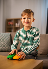 Image showing happy little boy playing with toy cars at home