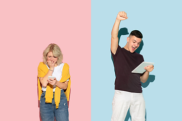 Image showing Young emotional man and woman on pink and blue background