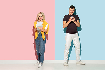 Image showing Young emotional man and woman on pink and blue background