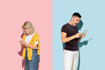 Image showing Young emotional man and woman on pink and blue background