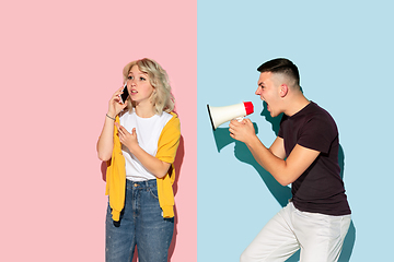 Image showing Young emotional man and woman on pink and blue background