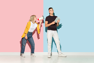 Image showing Young emotional man and woman on pink and blue background