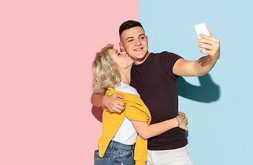 Image showing Young emotional man and woman on pink and blue background