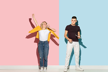 Image showing Young emotional man and woman on pink and blue background